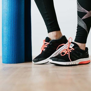 Woman in shoes with a yoga mat.