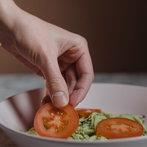 Hand picking a tomato slice out of a salad.