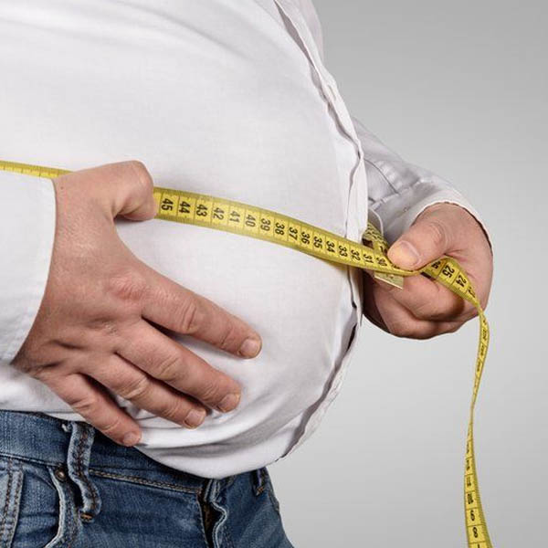 Overweight man measuring his belly.