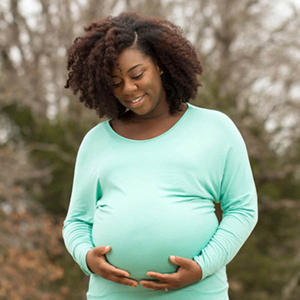 Woman smiling at her pregnant belly.