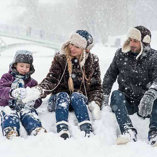 Mother, father, and baby sitting in snow.