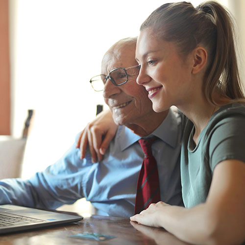 Young woman and old man looking at a laptop.